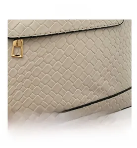 Détail de la texture tressée blanche d'un sac à bandoulière avec zip doré carré