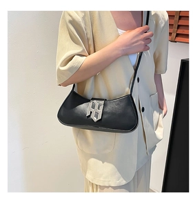 Détail du sac baguette en cuir PU noir avec une grande boucle géométrique en métal argenté