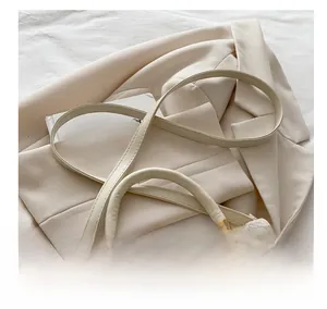 Detail of cream crossbody bag featuring woven texture and adjustable leather strap