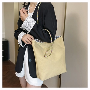 Detail of colorful beaded handle and classic black and white plaid lining on canvas tote