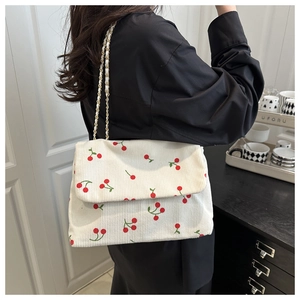 Détail du sac bandoulière en velours côtelé blanc avec imprimés cerises et chaîne dorée