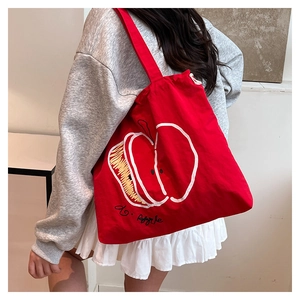 Close-up of red canvas tote bag with white apple illustration and do Apple lettering