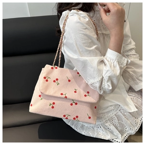 Détail du sac à bandoulière en velours côtelé rose avec imprimé cerises et chaîne dorée