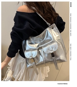 Detail of silver metallic tote bag with dual buckle flap pockets and industrial hardware
