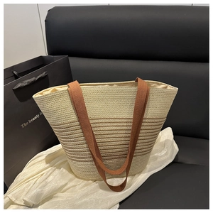 Close-up of woven straw tote bag with brown stripes and durable fabric handles