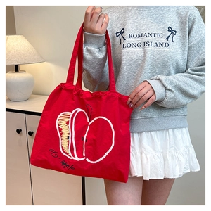 Detail of red nylon tote bag with artistic apple print for commuting and daily use