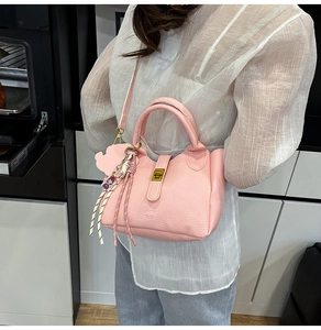 Detailed view of a pink lychee pattern bucket bag carried by a model in a modern kitchen