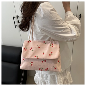 Gros plan détaillé du sac bandoulière en velours côtelé rose avec motif cerise et chaîne