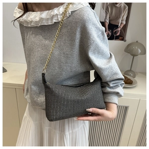 Détail du sac à main tissé avec bandoulière dorée sur un mannequin dans un intérieur
