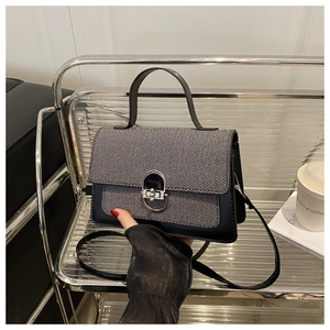 Detail of grey and black patchwork crossbody bag with silver buckle on a stylish stand