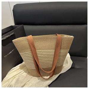 Close-up of beige straw tote bag with brown woven straps in a stylish indoor setting