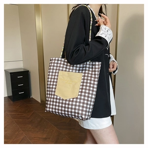 Detail of plaid tote bag featuring a yellow front pocket and colorful braided rope strap