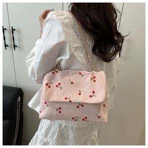 Détail du sac à bandoulière en velours côtelé rose avec imprimés cerises et chaîne