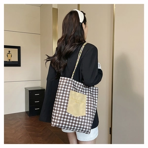 Detailed close-up of plaid canvas tote bag with yellow pocket and woven rope straps