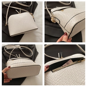 Détail du sac coquille blanc texturé avec fermeture éclair dorée et bandoulière fine