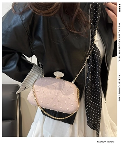 Detail showing pink embroidery on evening clutch with a sparkling rhinestone clasp and gold chain