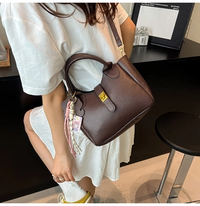Chic brown lychee grain leather bucket bag shown in a stylish lifestyle model street shot