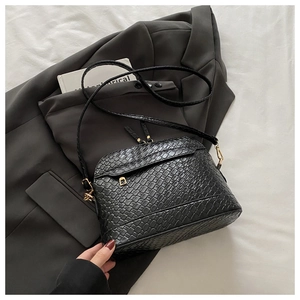 Detail of black woven texture handbag with dual zippers and gold hardware on blazer