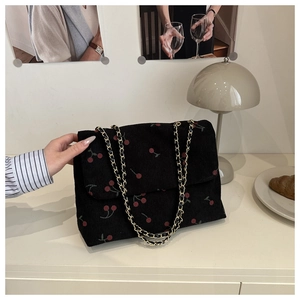 Gros plan du sac en velours côtelé avec imprimé cerise et détail de bandoulière dorée