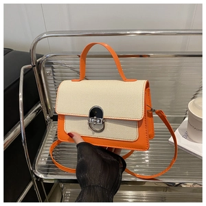 Close-up of contrast stitching on square crossbody bag with metallic oval twist lock