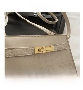 Detail of off-white crocodile texture handbag with golden metal twist lock closure
