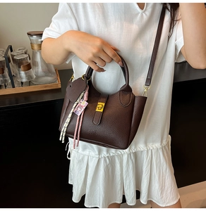 Close-up of a dark brown leather bucket bag with lychee texture held by a model