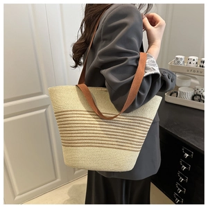 Detail of minimalist woven tote bag with brown stripes worn with grey blazer outfit