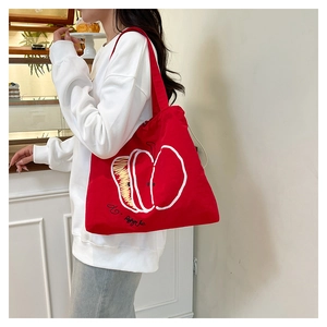 Detail of red nylon tote bag featuring apple print worn by a model on shoulder