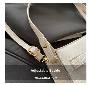 Macro detail of adjustable buckle and texture on white crocodile pattern underarm bag