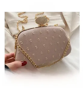 Detail of dusty rose chain bag featuring a rhinestone oval buckle and grainy fabric texture