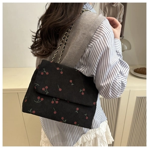 Détail du sac cabas en velours noir à imprimé cerise avec bandoulière chaîne dorée