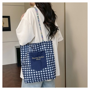 Detail of blue plaid tote bag with external pocket and woven multicolor rope strap