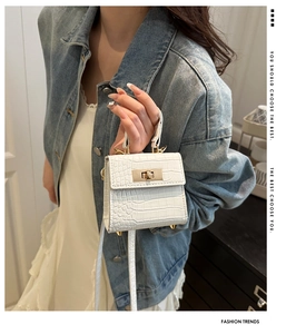 Detail of white crocodile embossed mini bag with gold twist lock and top handle