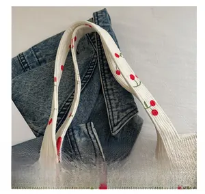 Gros plan du sac cabas en velours côtelé blanc avec motif cerises et détails de l'anse