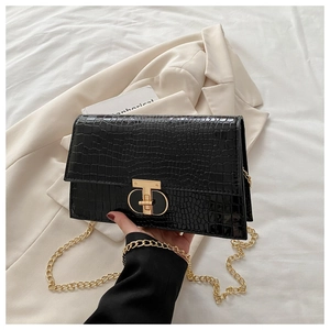 Detailed view of crocodile embossed leather handbag with gold T-bar twist lock and chain strap