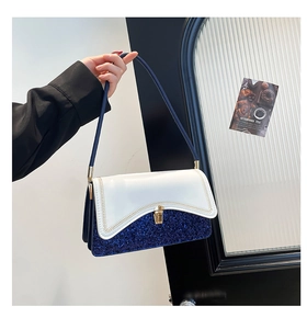 Detail of sequin texture and golden twist lock on a navy and white contrast handbag