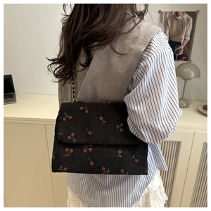 Détail du sac bandoulière en velours côtelé avec imprimé cerise et chaîne en métal