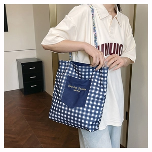 Detail showing blue and white plaid tote bag with colorful braided rope strap and pocket