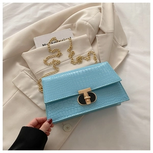 Macro view of light blue crocodile embossed leather texture and gold T-lock clasp detail