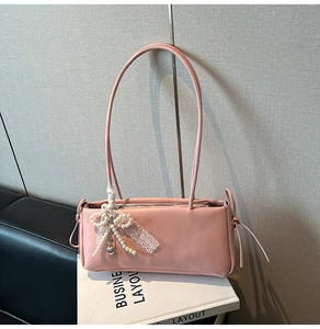 Detail of pink underarm bag with pearl lace bow charm and minimalist design