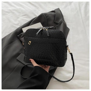 Detail of black faux crocodile leather crossbody bag with dual zippers and gold buckle