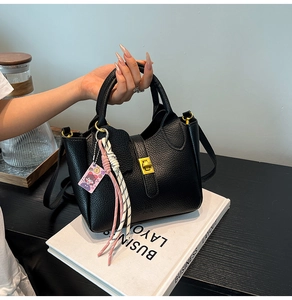 Close-up view of an elegant black litchi pattern leather bucket bag with a stylish pendant
