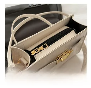 Close-up of white crocodile texture handbag showing golden metal zipper and lock detail