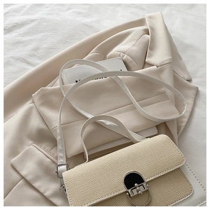 Close-up of the woven texture and metal twist lock on the cream white square shoulder bag