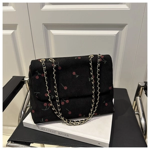 Vue détaillée du sac bandoulière en velours côtelé noir avec motifs cerises et chaîne