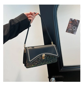 Close-up of black leather bag with rainbow glitter panel and white wavy stitching
