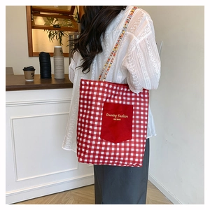 Detail view of red gingham tote bag with embroidered pocket and colorful woven straps