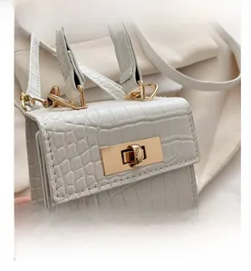 Macro detail of white faux crocodile embossed leather handbag with golden lock buckle