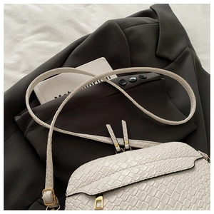 Detail of white crocodile embossed crossbody bag with elegant gold metal buckle accent