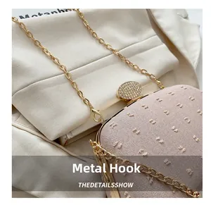 Macro detail of pale pink textured clutch with gold chain hook and rhinestone clasp